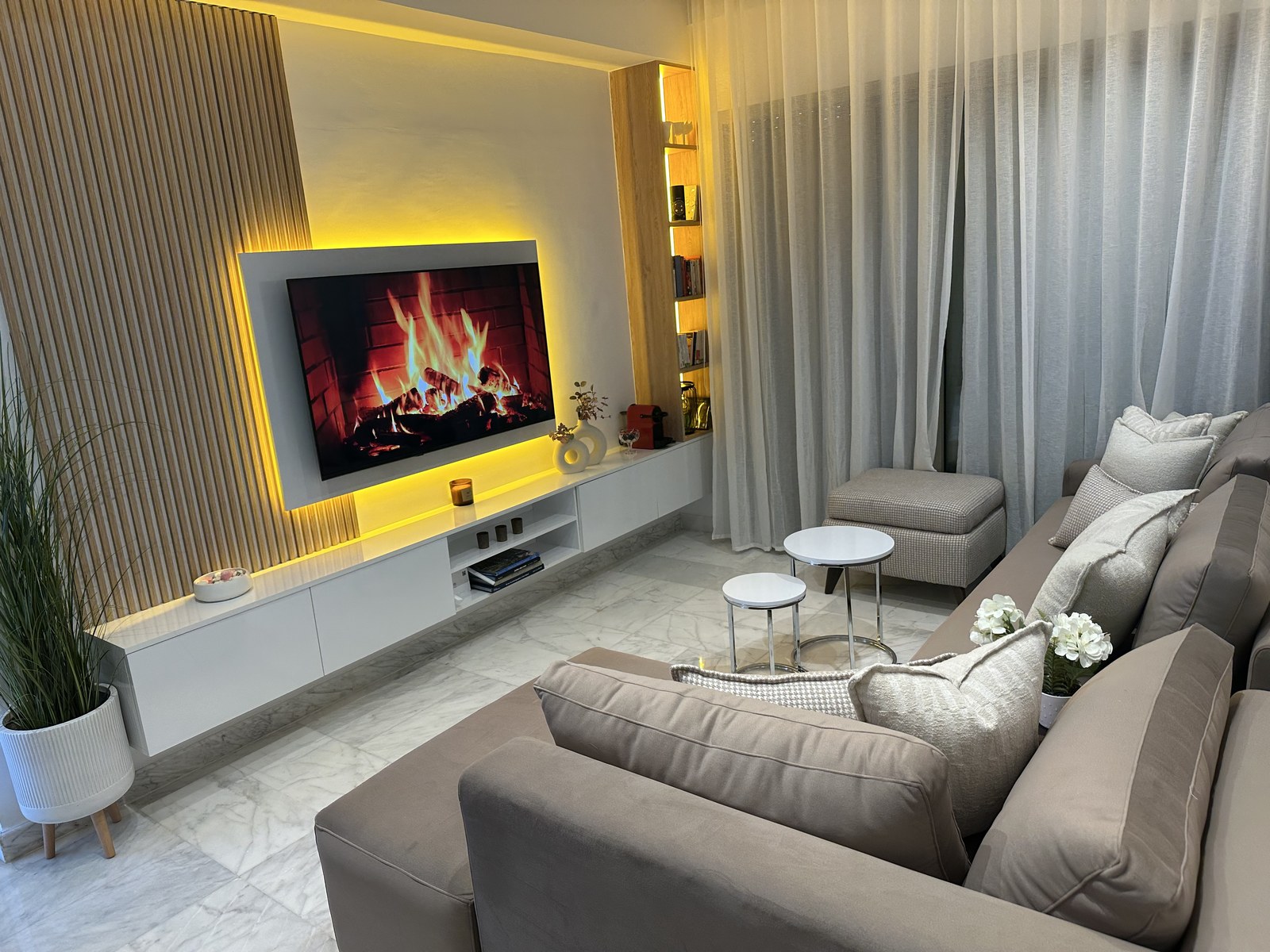 Actif locatif Airbnb à Zenata — Salon contemporain lumineux avec cheminée d'ambiance et rideaux blancs
